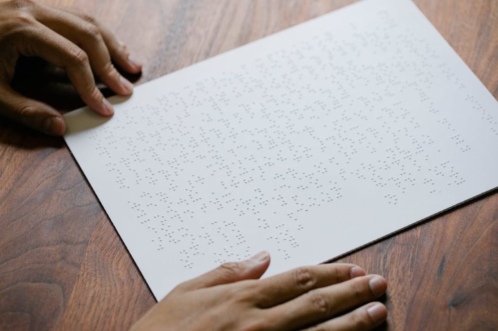 Close-up of hands feeling Braille text on paper, focusing on tactile reading skills.